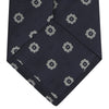 View 4 of product The Turnbull & Asser Navy and Silver Emblem Spot Silk Tie features a refined repeating emblem pattern in silver on navy silk, making it an elegant accessory for any office shirt.