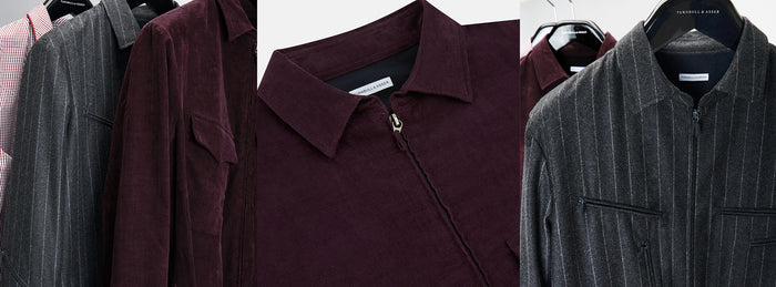 Several jackets in different fabrics and patterns, including burgundy corduroy, grey pinstripe, and red gingham, hang on black hangers against a white background.