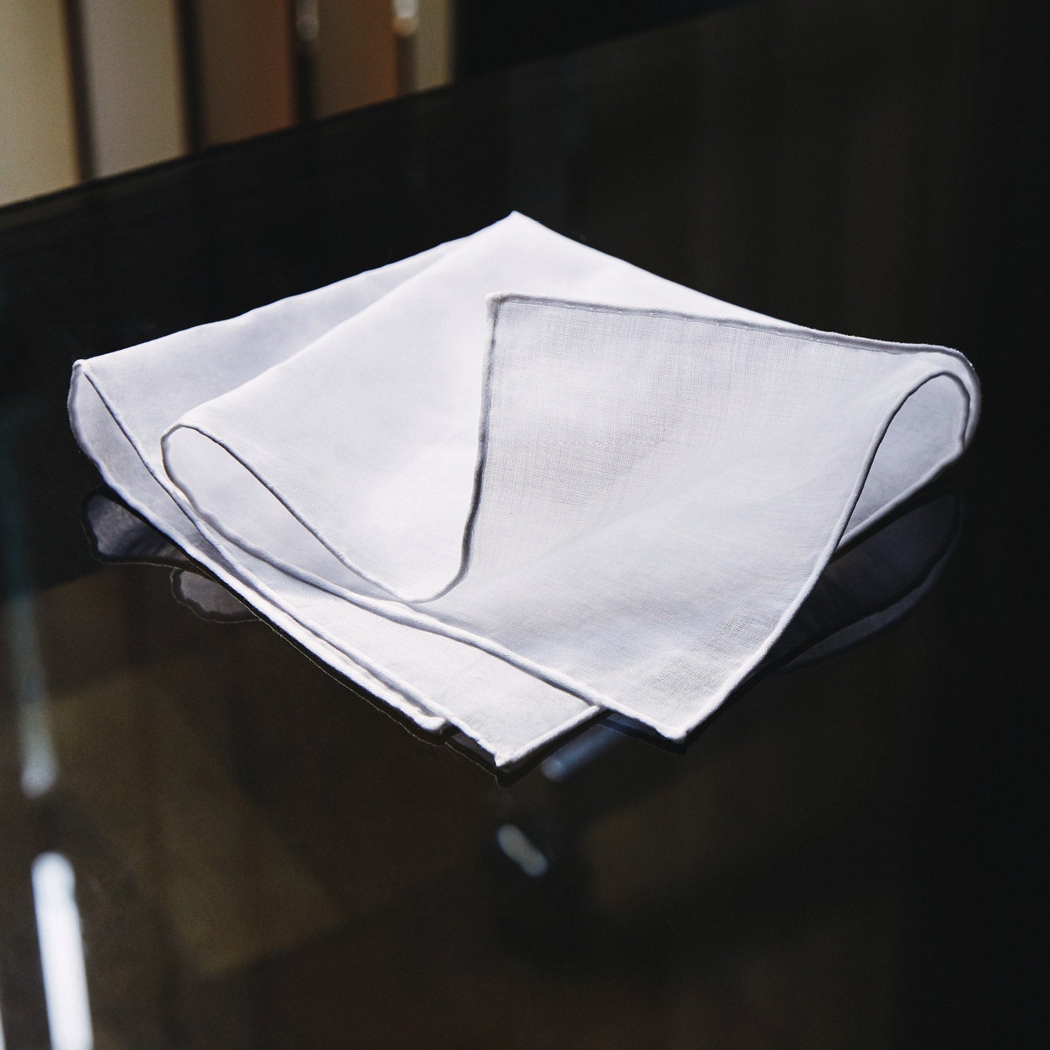 View 2 of product The James Bond Voile Pocket Square by Turnbull & Asser, in plain white with hand-rolled edges, is neatly folded and laid flat on a white background—a classic accessory for timeless style.