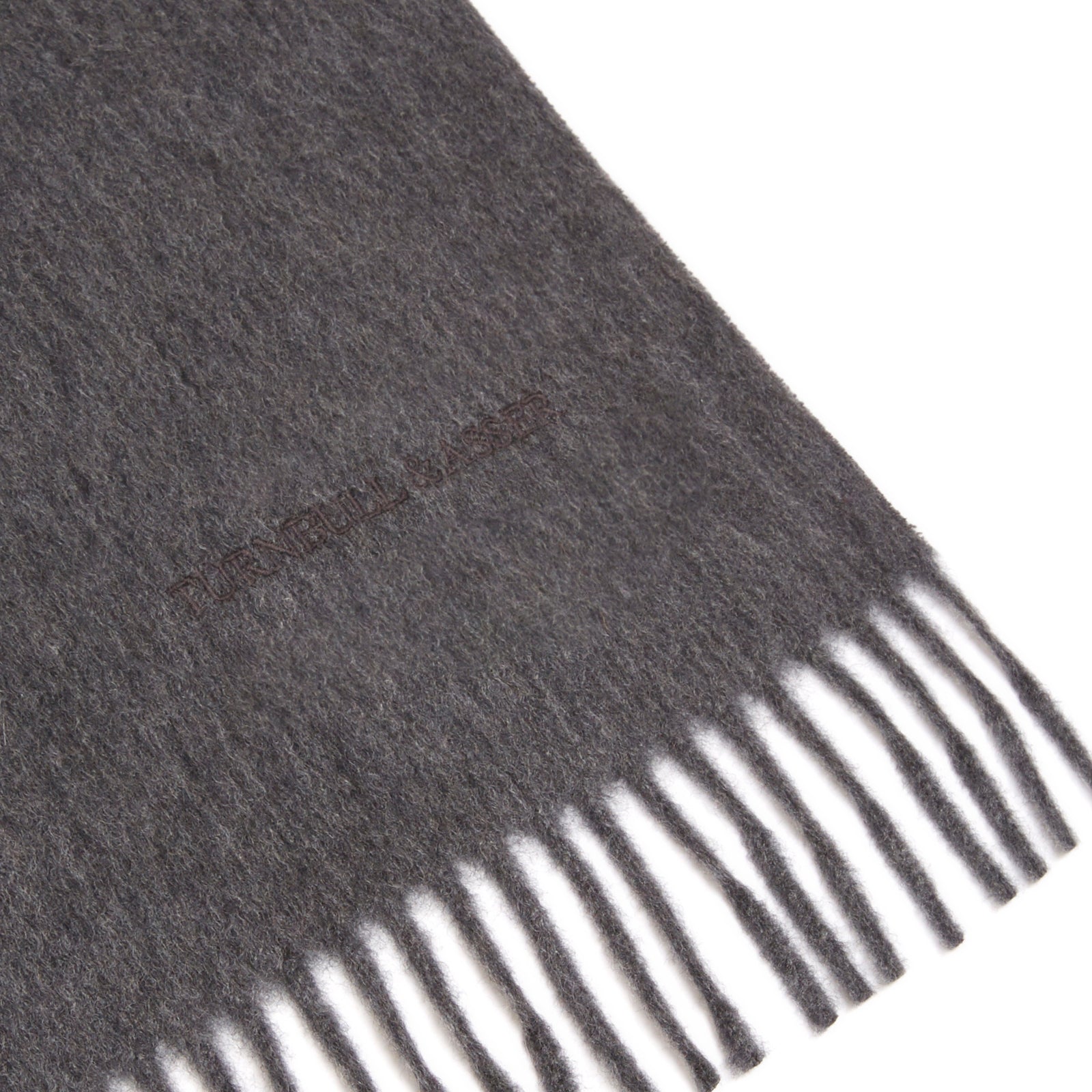 View 2 of product A sartorial essential, the Turnbull & Asser Dark Grey Pure Cashmere Scarf features fringed ends and is shown neatly folded on a plain white background.