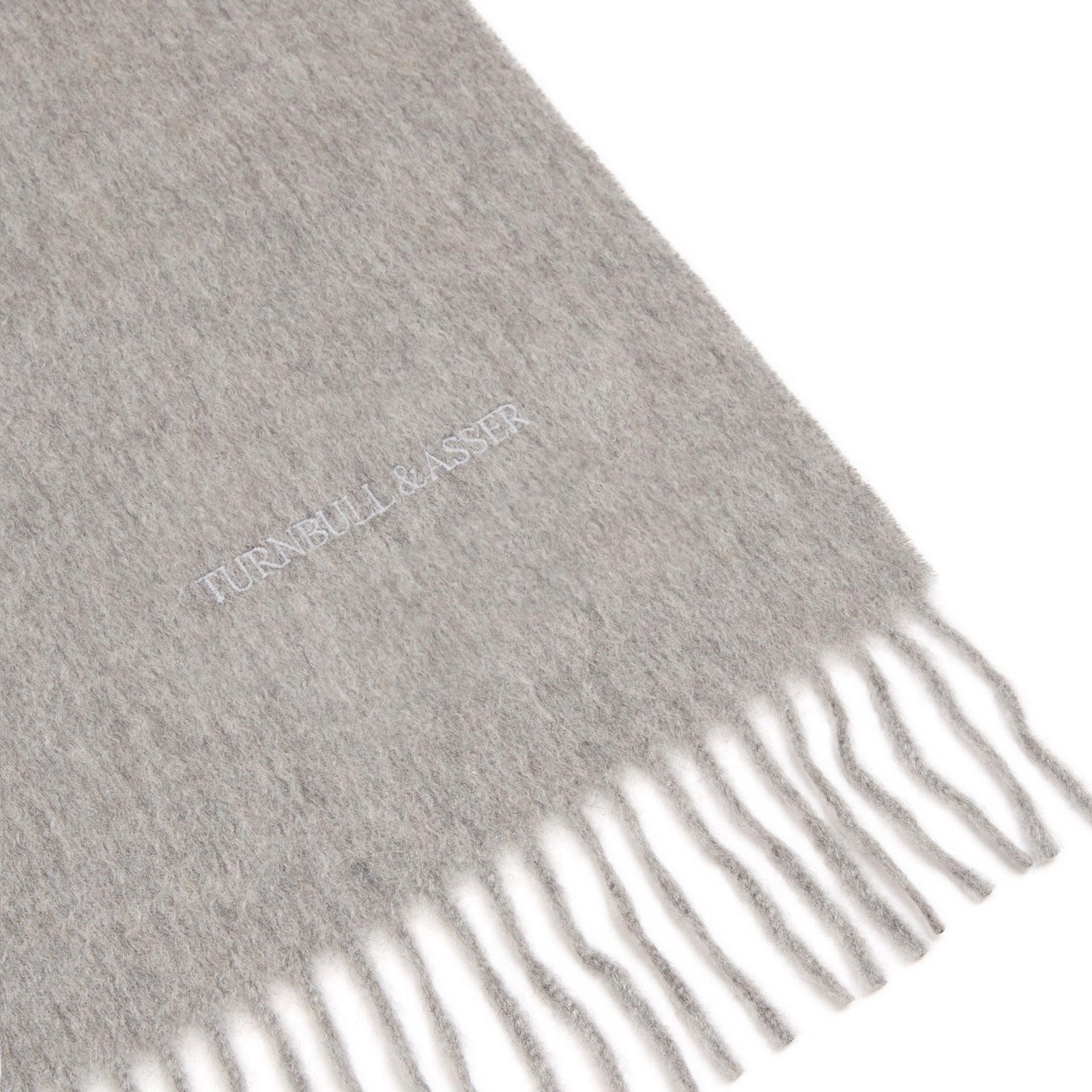 View 2 of product The Flannel Grey Pure Cashmere Scarf by Turnbull & Asser is crafted from soft cashmere, showcased neatly folded with fringed ends on a plain white background.