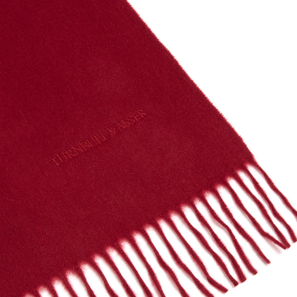The Turnbull & Asser Bordeaux Pure Cashmere Scarf, in deep red with a soft texture and fringed ends, is neatly folded and displayed on a plain white background.