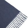 View 2 of product The Turnbull & Asser Slate Pure Cashmere Scarf is a luxurious navy blue accessory with fringed ends, neatly folded and showcased on a plain white background.