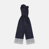 View 1 of product The Turnbull & Asser Navy and White Spotted Silk Scarf with Fringes, featuring small polka dots and grey fringe at both ends, is neatly folded and displayed on a plain white background.