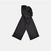 View 1 of product The Black and White Spotted Silk Scarf by Turnbull & Asser features small hand-printed white polka dots and short fringes, shown laid flat on a white background.