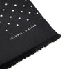 View 2 of product The Black and White Spotted Silk Scarf by Turnbull & Asser features small hand-printed white polka dots and short fringes, shown laid flat on a white background.
