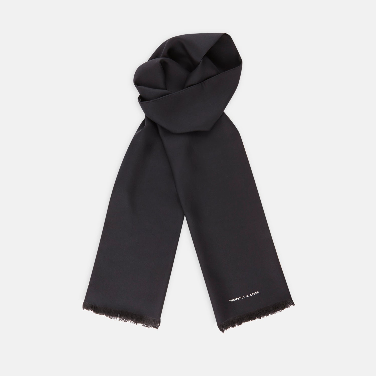 View 1 of product The Turnbull & Asser Plain Black Silk Scarf features fringed edges and subtle white branding at one end, ideal for formalwear or tuxedos, and is shown on a plain white background.