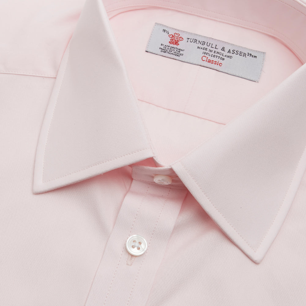 The Turnbull & Asser Pink Cotton Shirt features a T&A collar, 3-button cuffs, and a front pocket. Its clean-cut design is ideal for formal occasions and pairs well with masculine accessories. Displayed against a white background.