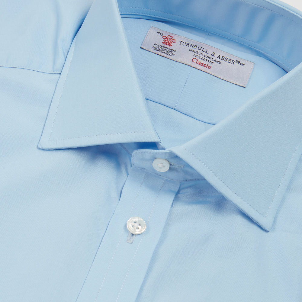 A Turnbull & Asser Blue Shirt with Regent Collar and 2-Button Cocktail Cuffs is neatly folded, featuring white buttons, and displayed on a plain white background.