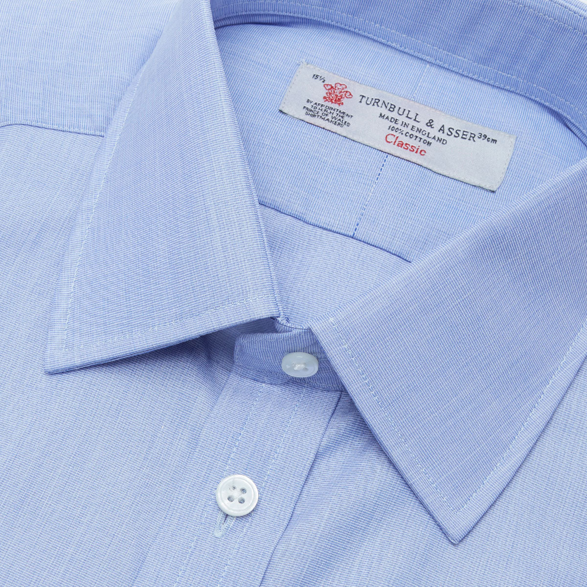 View 5 of product The Turnbull & Asser Blue End-on-End Cotton Shirt features a T&A collar, double cuffs, white buttons, and a chest pocket. Displayed neatly folded on a white background with the label visible at the neck—ideal for refined style.