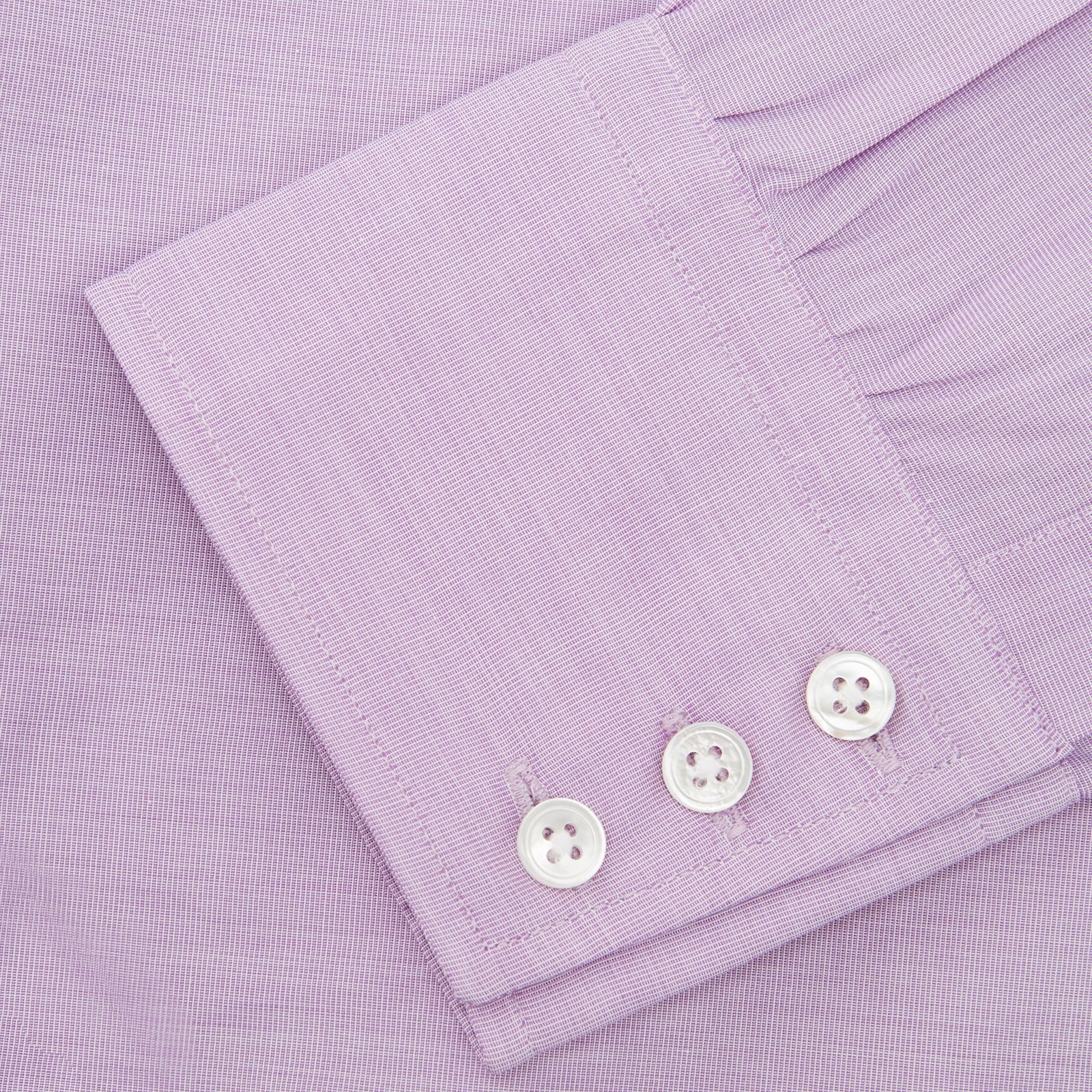 View 6 of product A neatly folded Turnbull & Asser Lilac End-on-End Shirt with T&A collar and 3-button cuffs, featuring white buttons and long sleeves, is displayed on a plain white background.