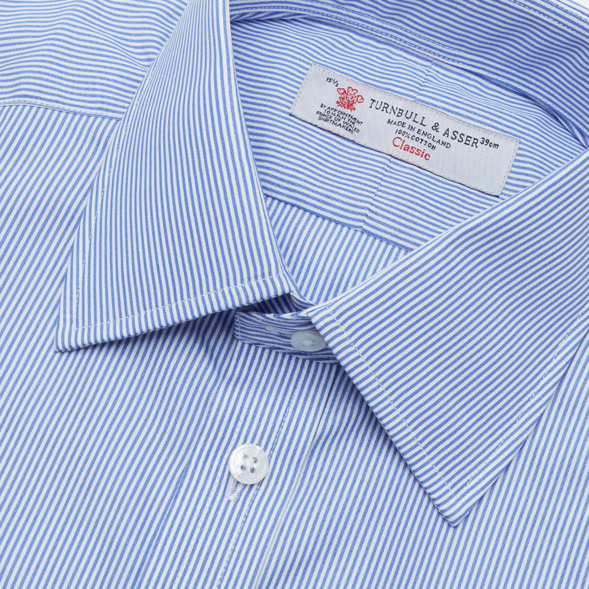 View 5 of product The Turnbull & Asser Blue Fine Bengal Stripe Shirt features a classic T&A collar, white buttons, and 3-button cuffs, displayed neatly folded against a plain white background.