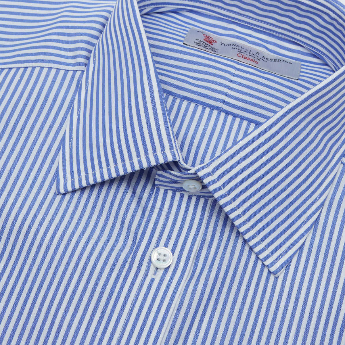 View 5 of product The Turnbull & Asser Blue Bengal Stripe Shirt features a T&A collar, double cuffs, and crisp white buttons. Made from cotton with blue and white bengal stripes, it’s neatly folded and displayed on a white background.