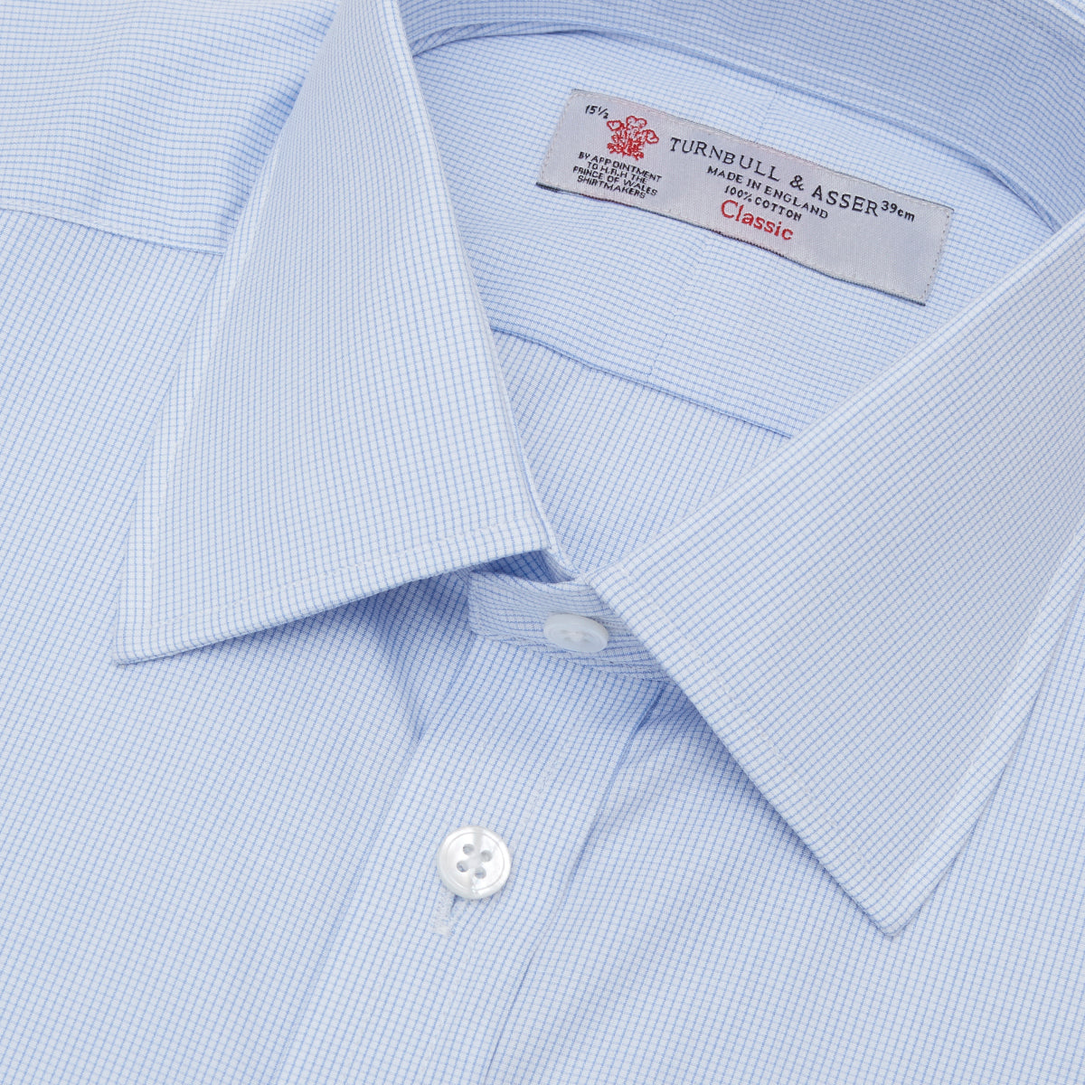 View 5 of product The Turnbull & Asser Light Blue Fine Check Shirt for men features a T&A collar, 3-button cuffs, classic white buttons, and a refined check design with a visible label inside the collar.