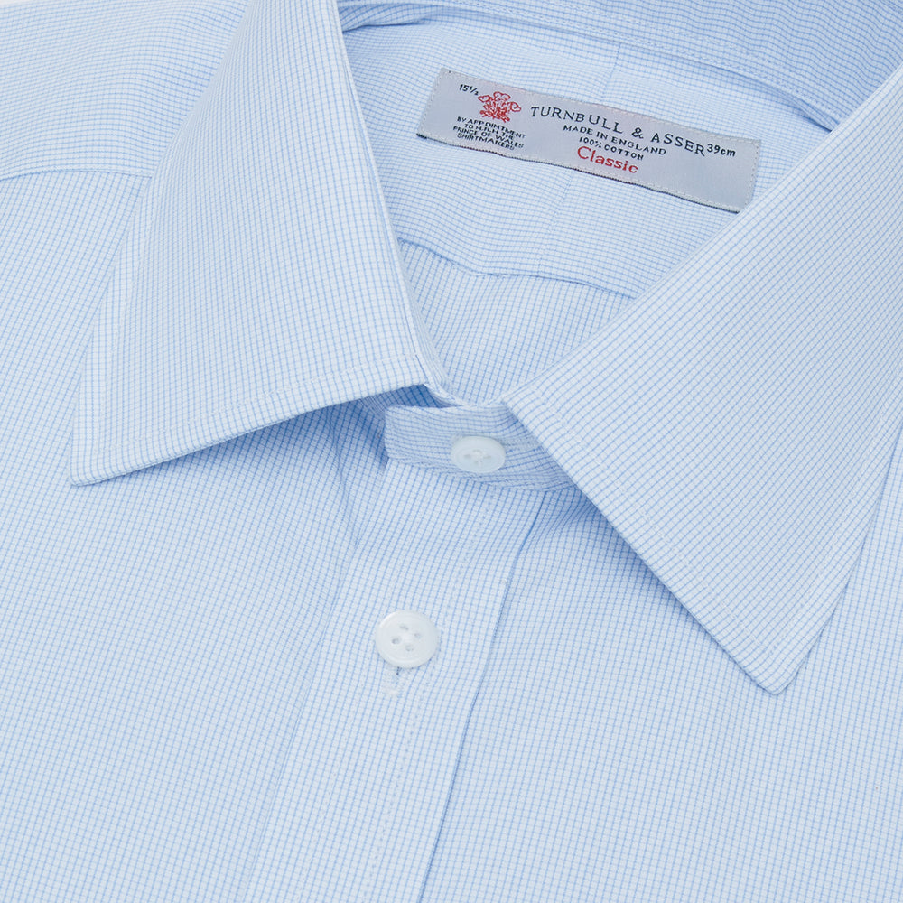Turnbull & Asser’s Light Blue Fine Check Shirt features a T&A collar, double cuffs, and a subtle checked cotton pattern, neatly displayed on a white background for a classic smart look.