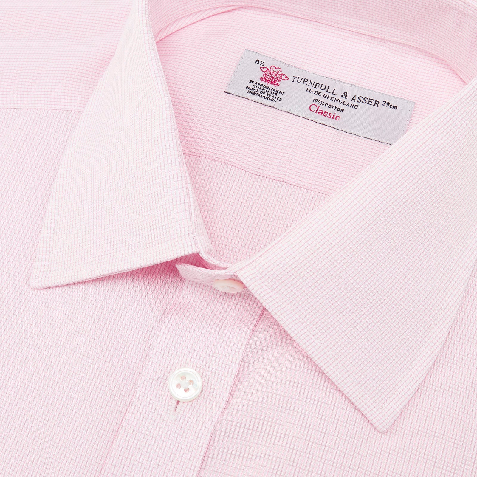 View 5 of product The Turnbull & Asser Pink Fine Check Shirt features a T&A collar, double cuffs, and classic white buttons, neatly folded and displayed against a plain white background.