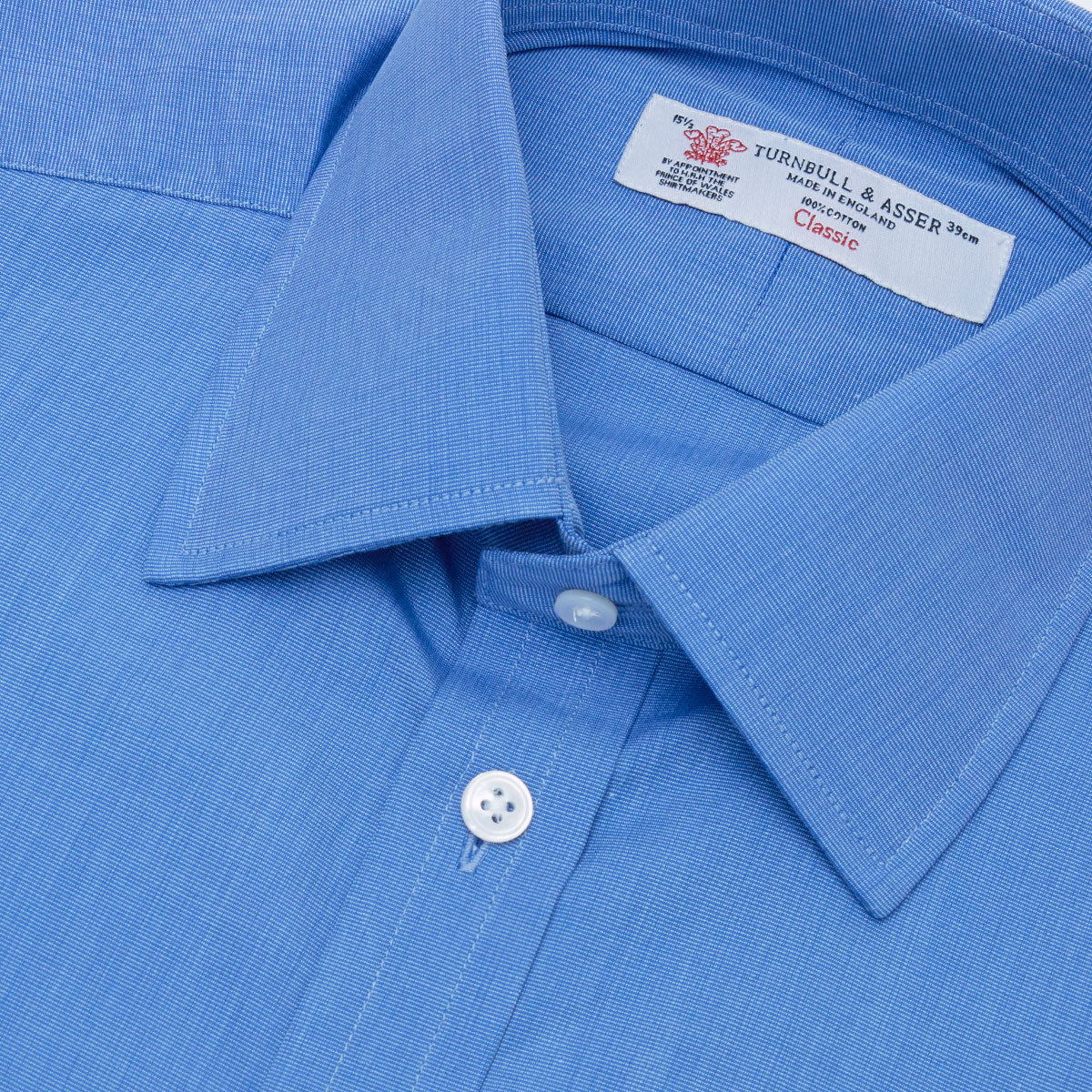 View 5 of product A neatly folded, dark blue end-on-end men's dress shirt by Turnbull & Asser, featuring a T&A collar and double cuffs, is displayed against a plain white background.