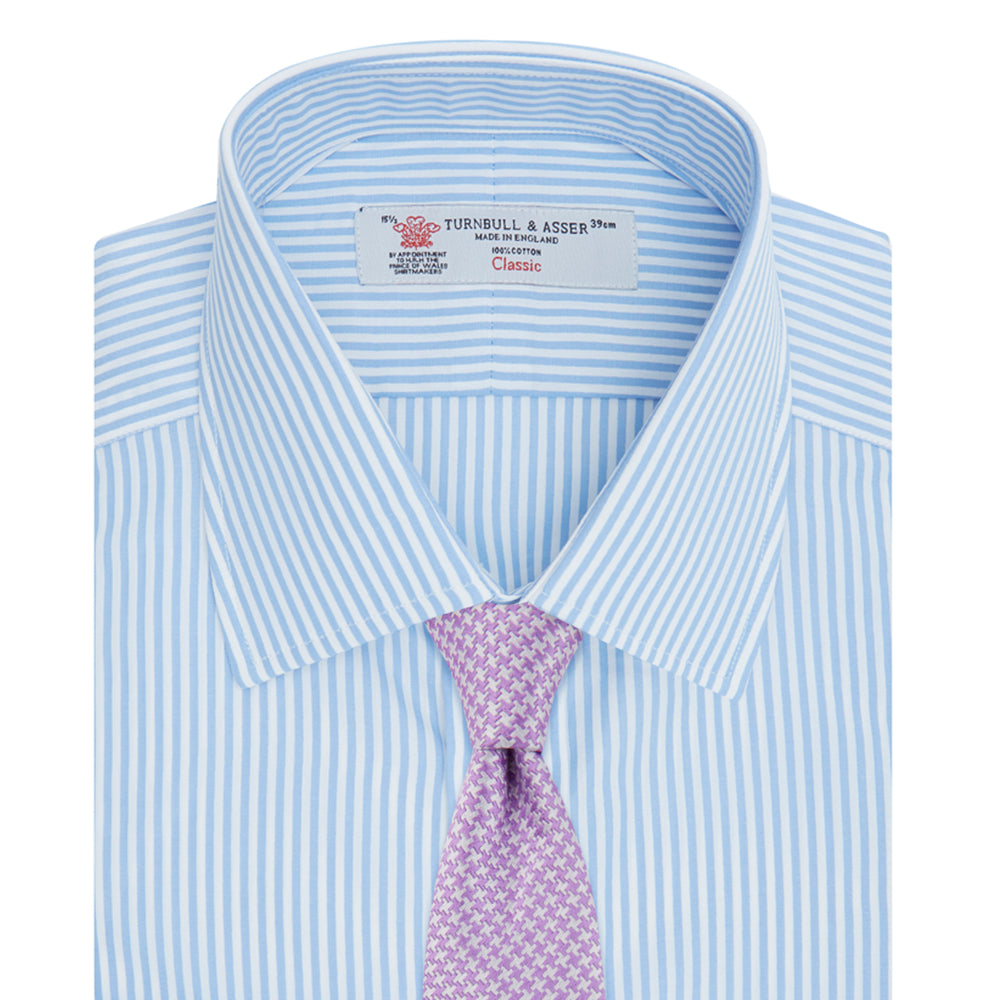 The Turnbull & Asser Light Blue Bengal Stripe Shirt features a T&A collar, double cuffs, and white buttons, offering British flair in blue and white stripes against a plain background.