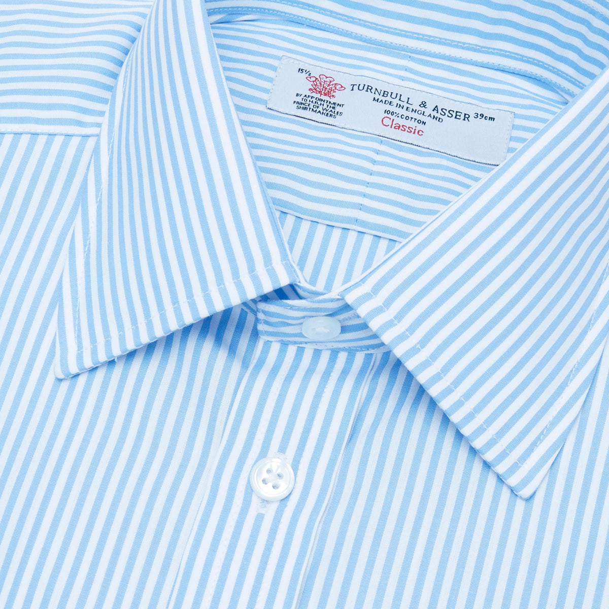 View 5 of product The Turnbull & Asser Light Blue Bengal Stripe Shirt features a T&A collar, double cuffs, and white buttons, offering British flair in blue and white stripes against a plain background.