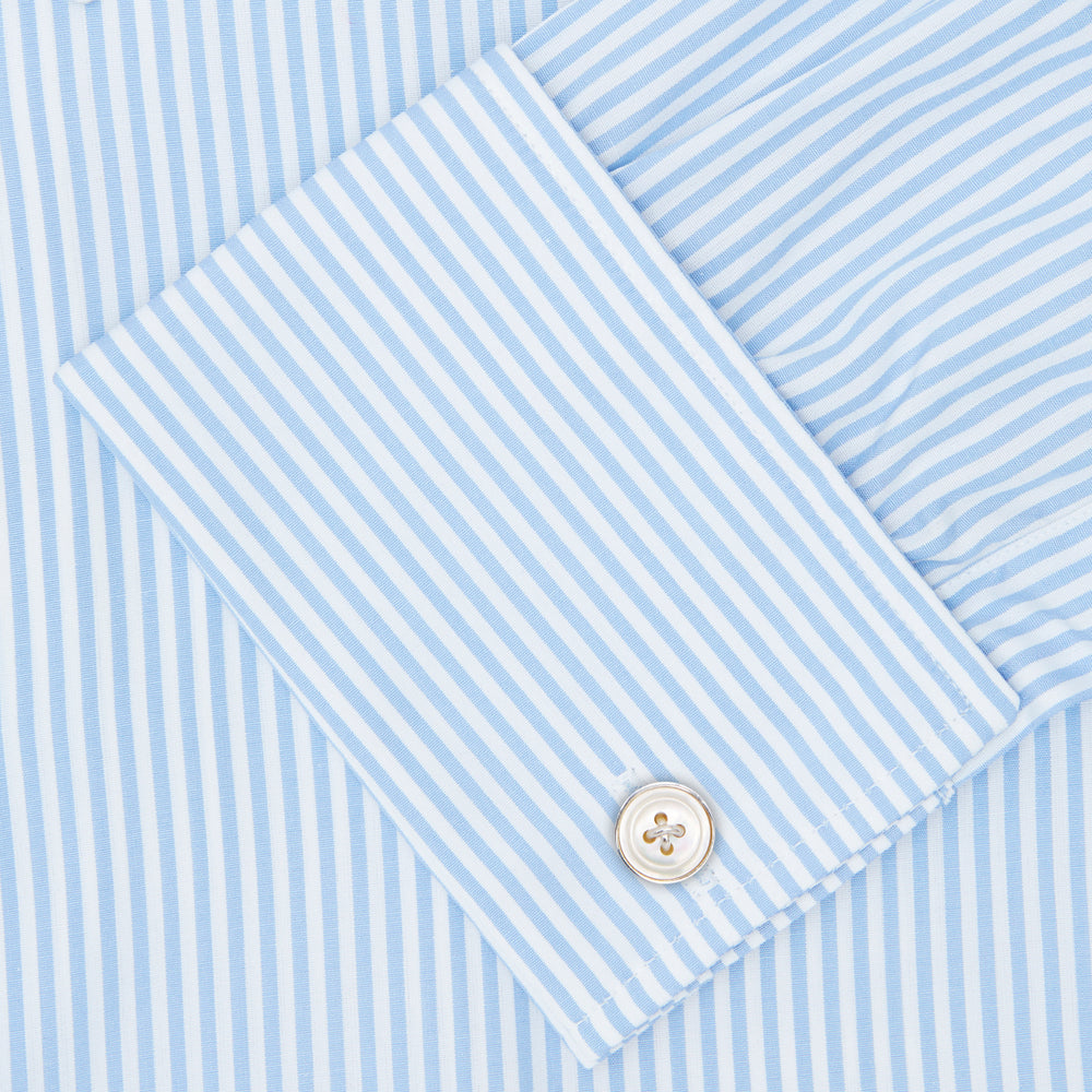 The Turnbull & Asser Light Blue Bengal Stripe Shirt features a T&A collar, double cuffs, and white buttons, offering British flair in blue and white stripes against a plain background.