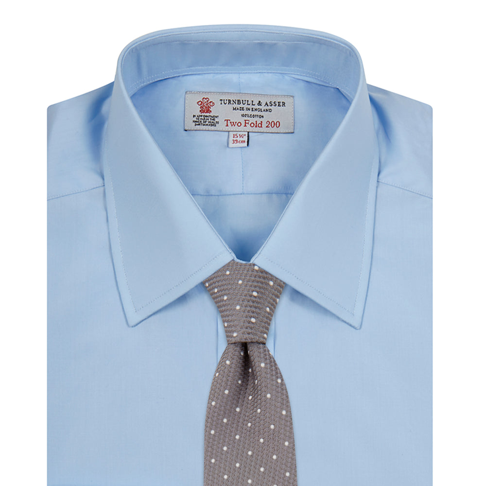 The Turnbull & Asser Two-Fold 200 Blue Cotton Shirt features a T&A collar, double cuffs, white buttons, and a visible label inside the collar, displayed neatly folded on a plain white background for superior breathability.