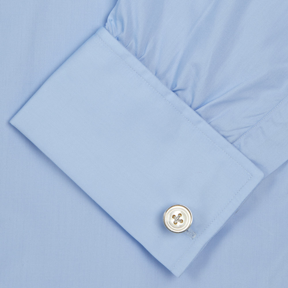 The Turnbull & Asser Two-Fold 200 Blue Cotton Shirt features a T&A collar, double cuffs, white buttons, and a visible label inside the collar, displayed neatly folded on a plain white background for superior breathability.