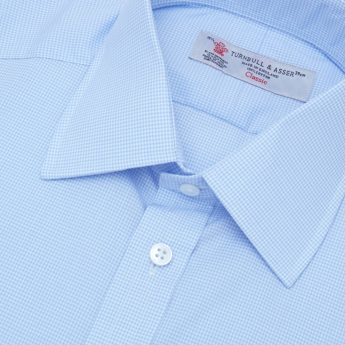 View 5 of product The Sky Blue Micro-Check Cotton Shirt by Turnbull & Asser features a T&A collar and 3-button cuffs, offering a refined take on classic British style. The shirt is neatly folded, showcasing its signature elegance against a white background.