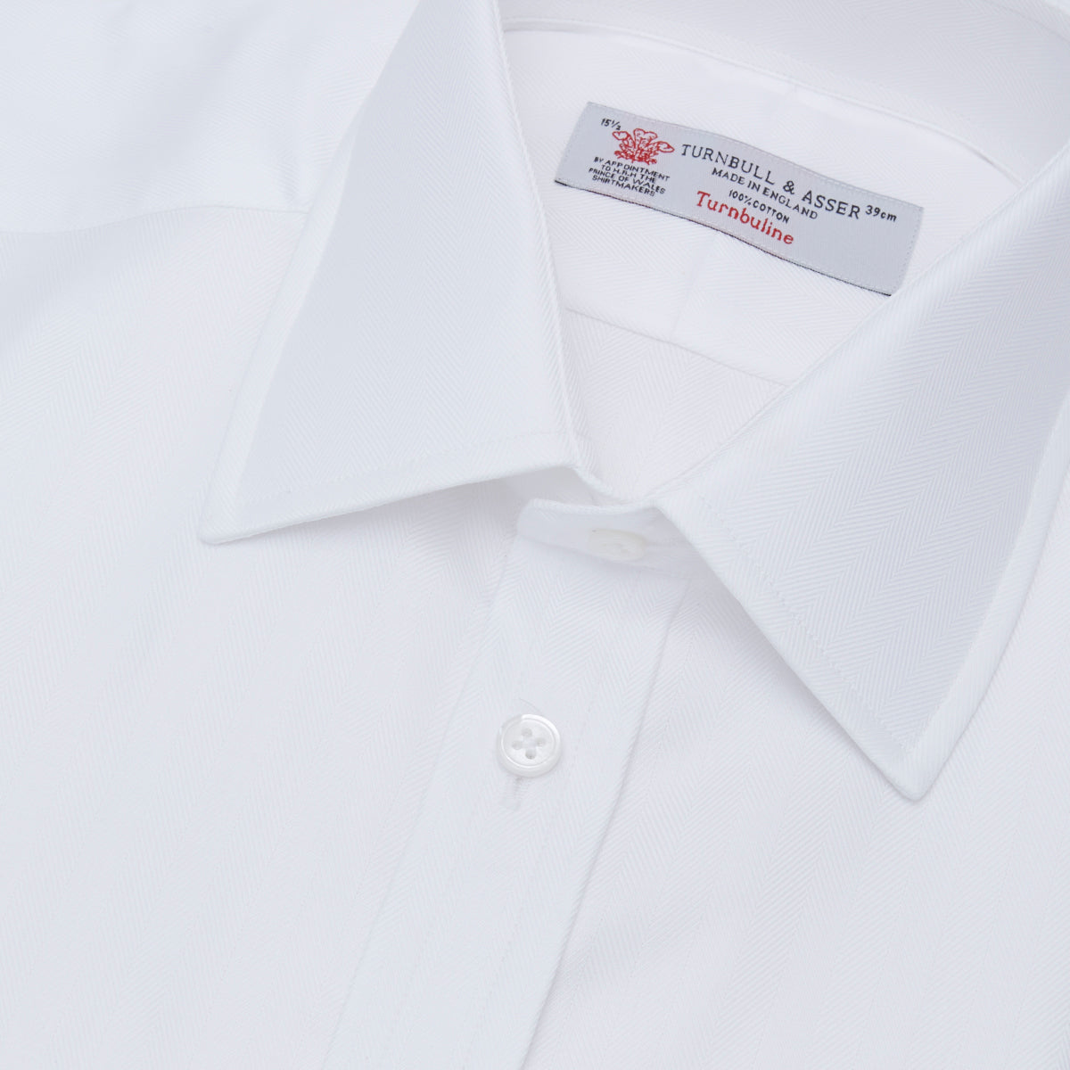 View 5 of product The Turnbull & Asser White Herringbone Superfine Cotton Shirt features a T&A collar and 3-button cuffs, displayed against a light blue background—ideal for minimalist styles or pairing with bold ties.