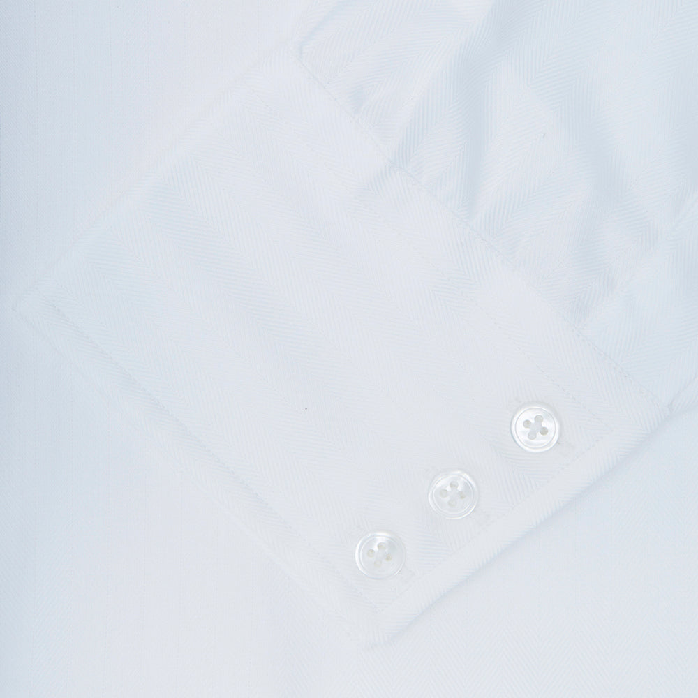 The Turnbull & Asser White Herringbone Superfine Cotton Shirt features a T&A collar and 3-button cuffs, displayed against a light blue background—ideal for minimalist styles or pairing with bold ties.