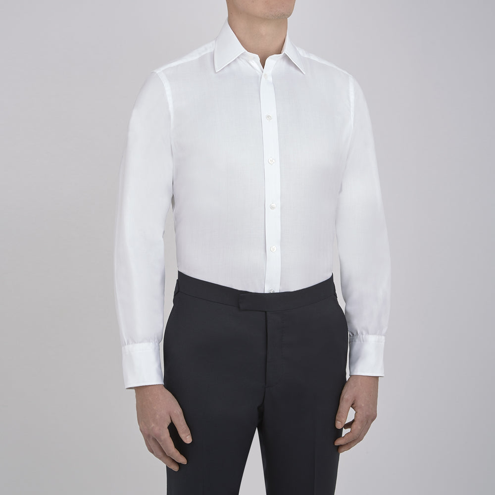 The Turnbull & Asser White Herringbone Superfine Cotton Shirt features a T&A collar and 3-button cuffs, displayed against a light blue background—ideal for minimalist styles or pairing with bold ties.
