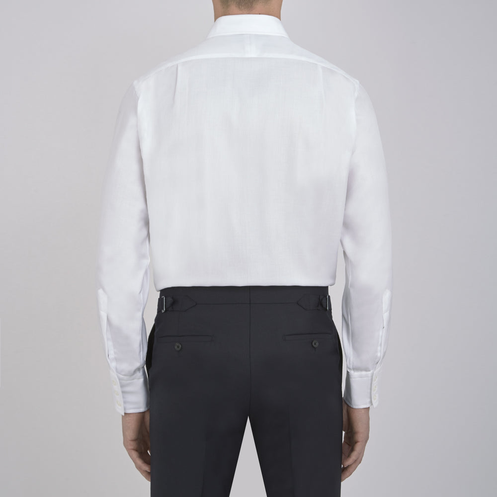 The Turnbull & Asser White Herringbone Superfine Cotton Shirt features a T&A collar and 3-button cuffs, displayed against a light blue background—ideal for minimalist styles or pairing with bold ties.