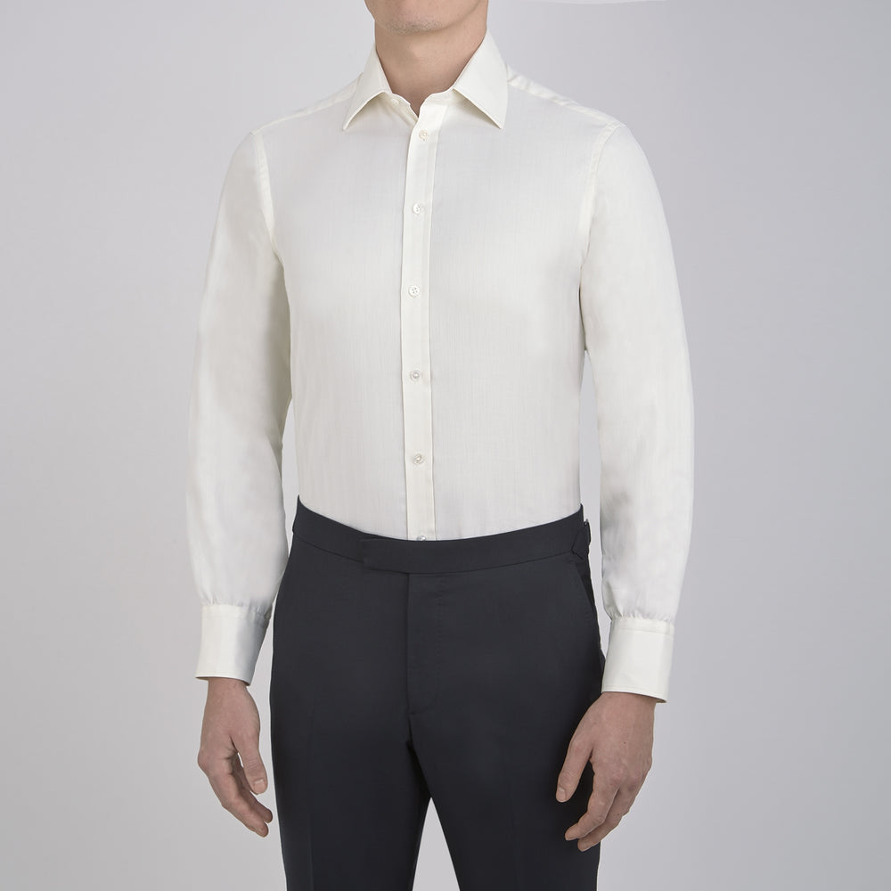 The Turnbull & Asser Cream Herringbone Superfine Cotton Shirt features a T&A collar and 3-button cuffs, ideal for minimalist style or bold ties, shown neatly folded against a plain white background.