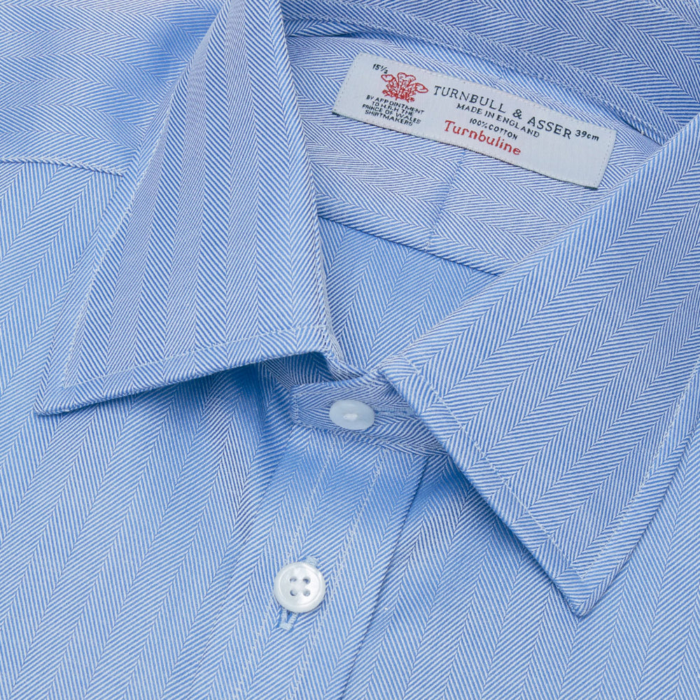 The Blue Herringbone Superfine Cotton Shirt by Turnbull & Asser features a T&A collar and 3-button cuffs, offering a refined minimalist look. Displayed against a plain white background.