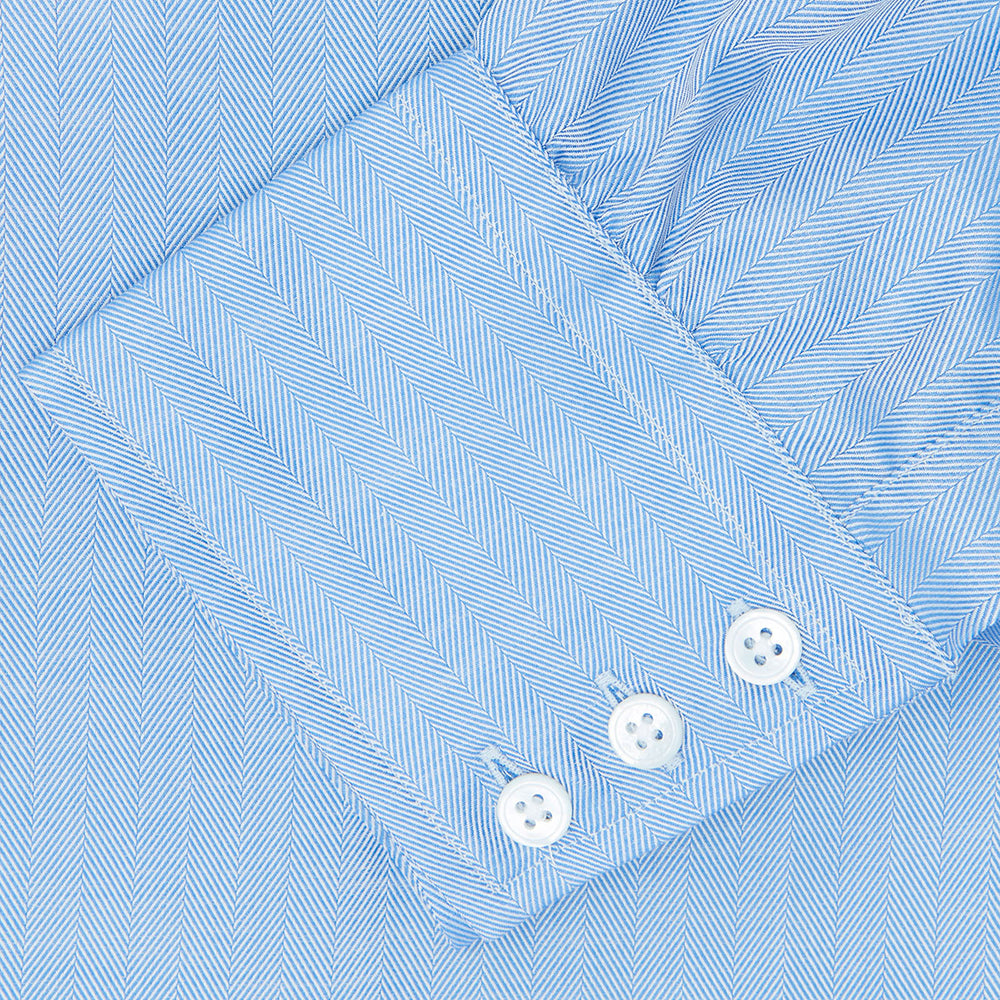 The Blue Herringbone Superfine Cotton Shirt by Turnbull & Asser features a T&A collar and 3-button cuffs, offering a refined minimalist look. Displayed against a plain white background.