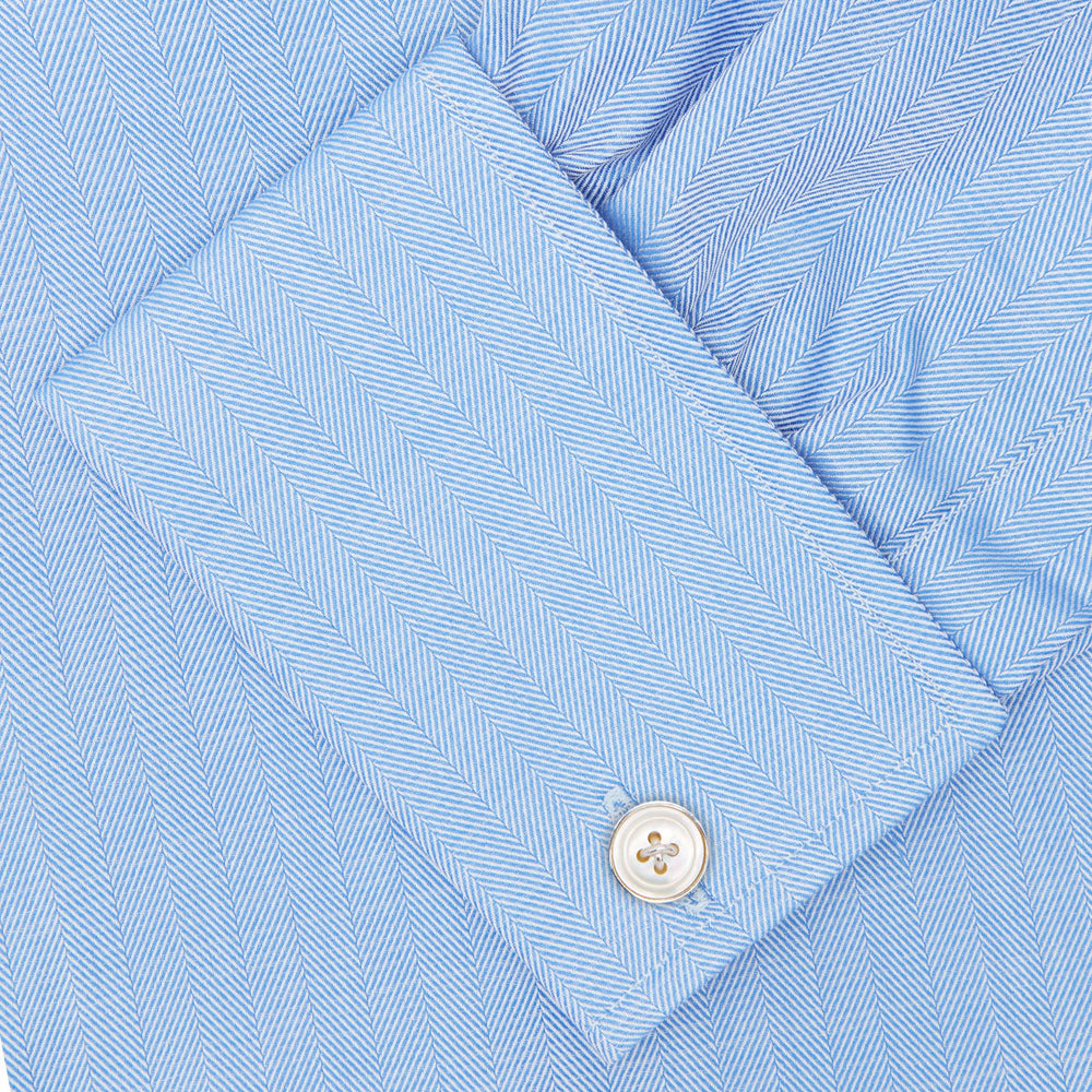 The Turnbull & Asser Blue Herringbone Superfine Cotton Shirt features a T&A collar and double cuffs—an essential for discerning gentlemen—shown folded on a plain white background.