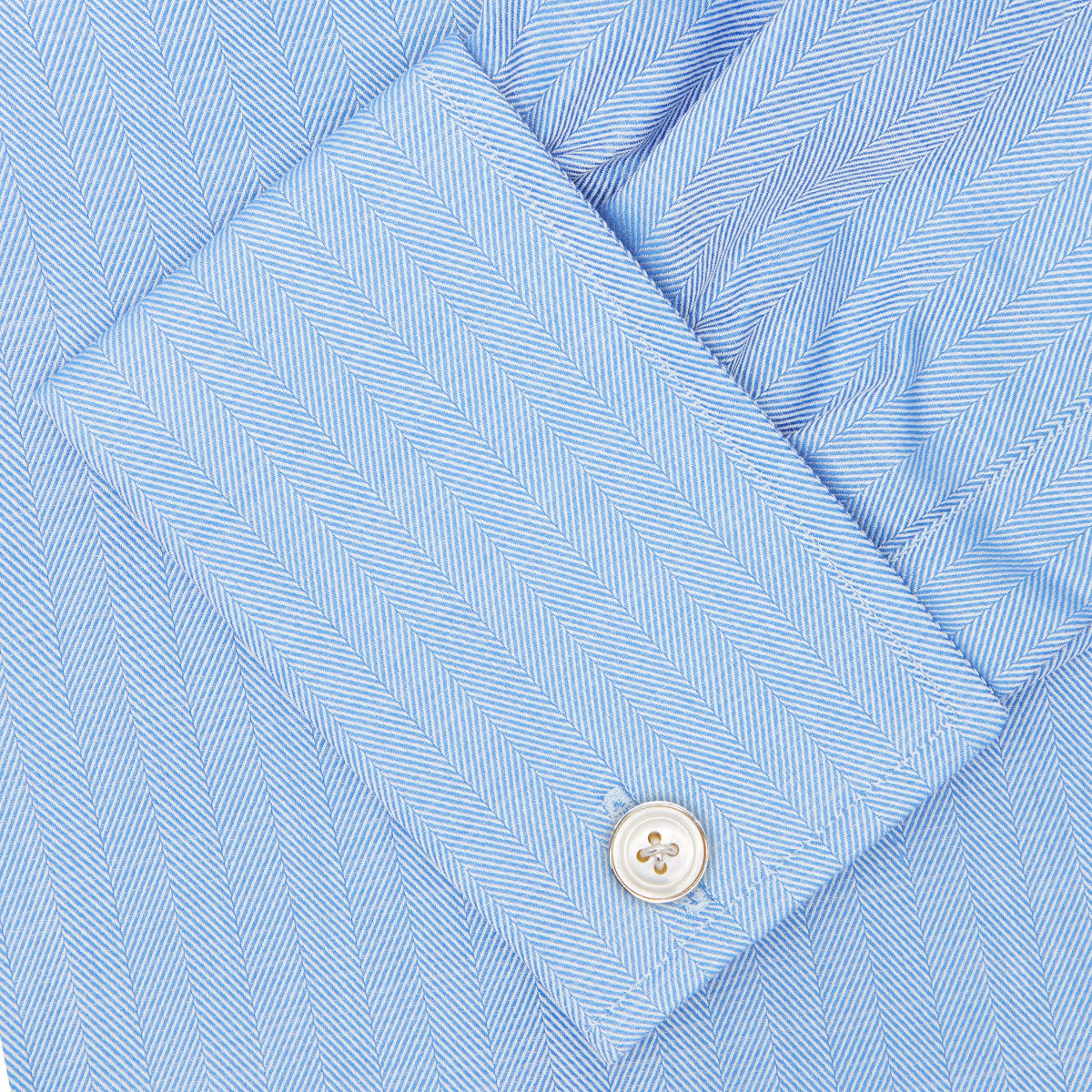 View 6 of product The Turnbull & Asser Blue Herringbone Superfine Cotton Shirt features a T&A collar and double cuffs—an essential for discerning gentlemen—shown folded on a plain white background.