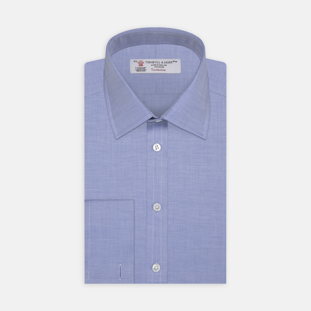The Turnbull & Asser Blue Herringbone Superfine Cotton Shirt features a T&A collar and double cuffs—an essential for discerning gentlemen—shown folded on a plain white background.