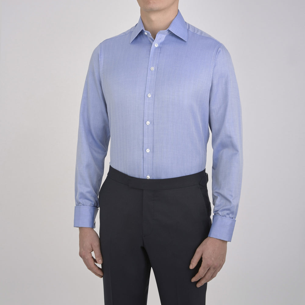 The Turnbull & Asser Blue Herringbone Superfine Cotton Shirt features a T&A collar and double cuffs—an essential for discerning gentlemen—shown folded on a plain white background.