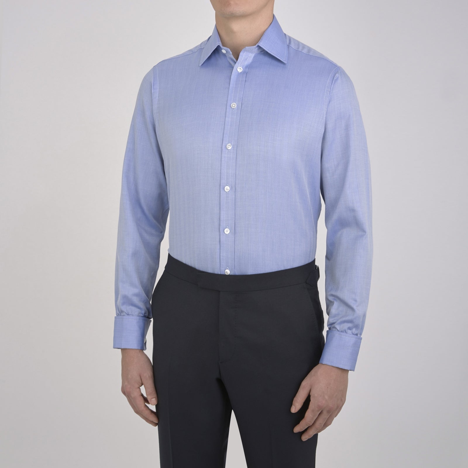 View 2 of product The Turnbull & Asser Blue Herringbone Superfine Cotton Shirt features a T&A collar and double cuffs—an essential for discerning gentlemen—shown folded on a plain white background.