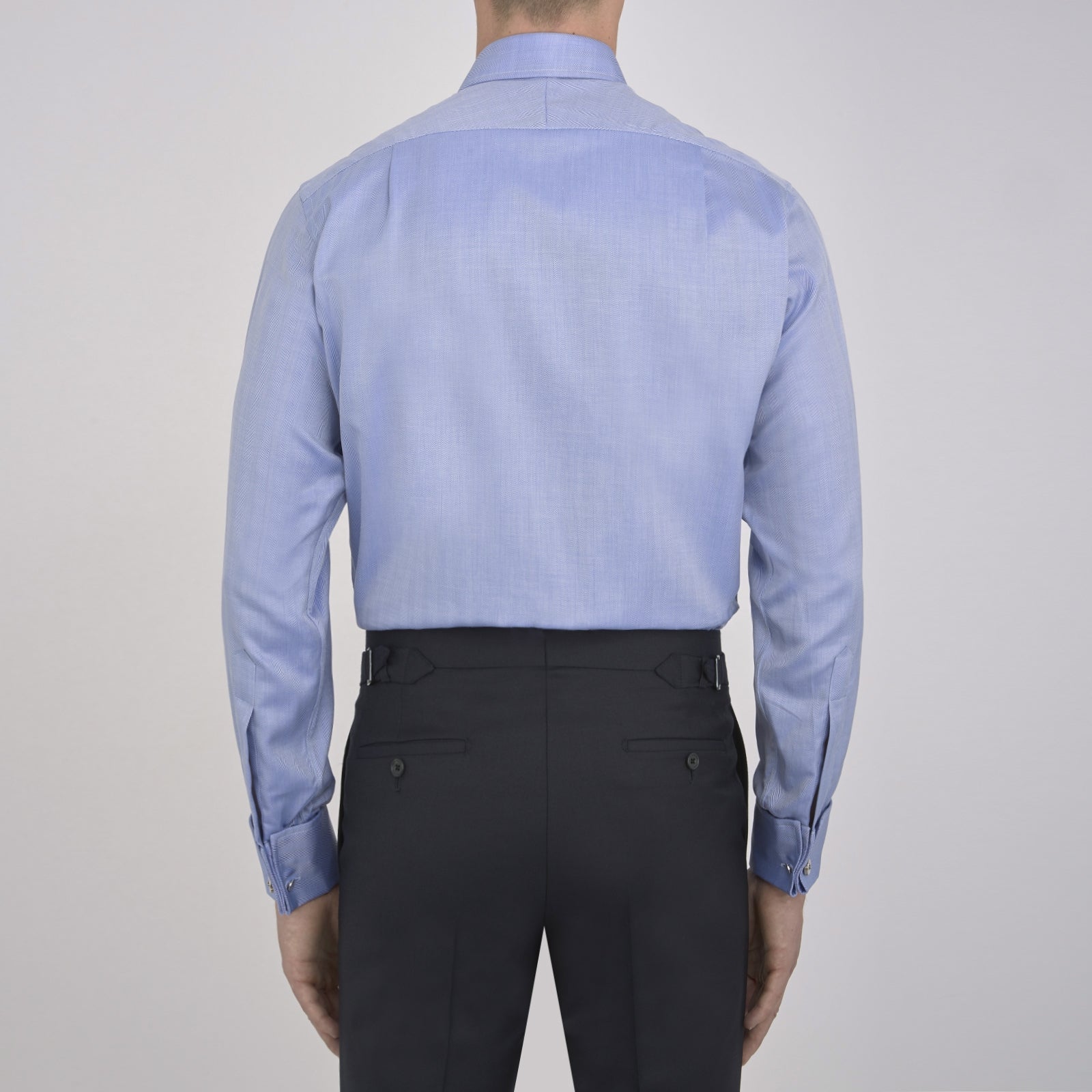 View 3 of product The Turnbull & Asser Blue Herringbone Superfine Cotton Shirt features a T&A collar and double cuffs—an essential for discerning gentlemen—shown folded on a plain white background.