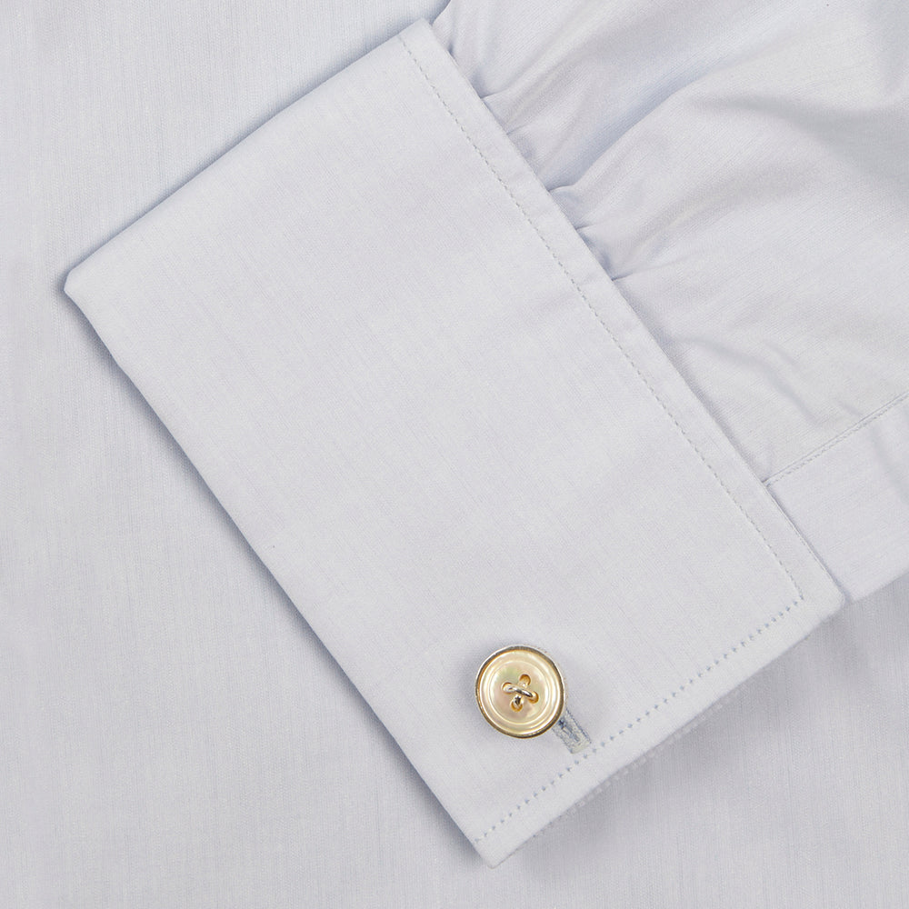 A neatly folded light blue long-sleeve dress shirt with a pointed collar and white buttons, styled with the Turnbull & Asser Monochrome Paisley Mill Silk Pocket Square (limited edition), displayed against a plain white background.