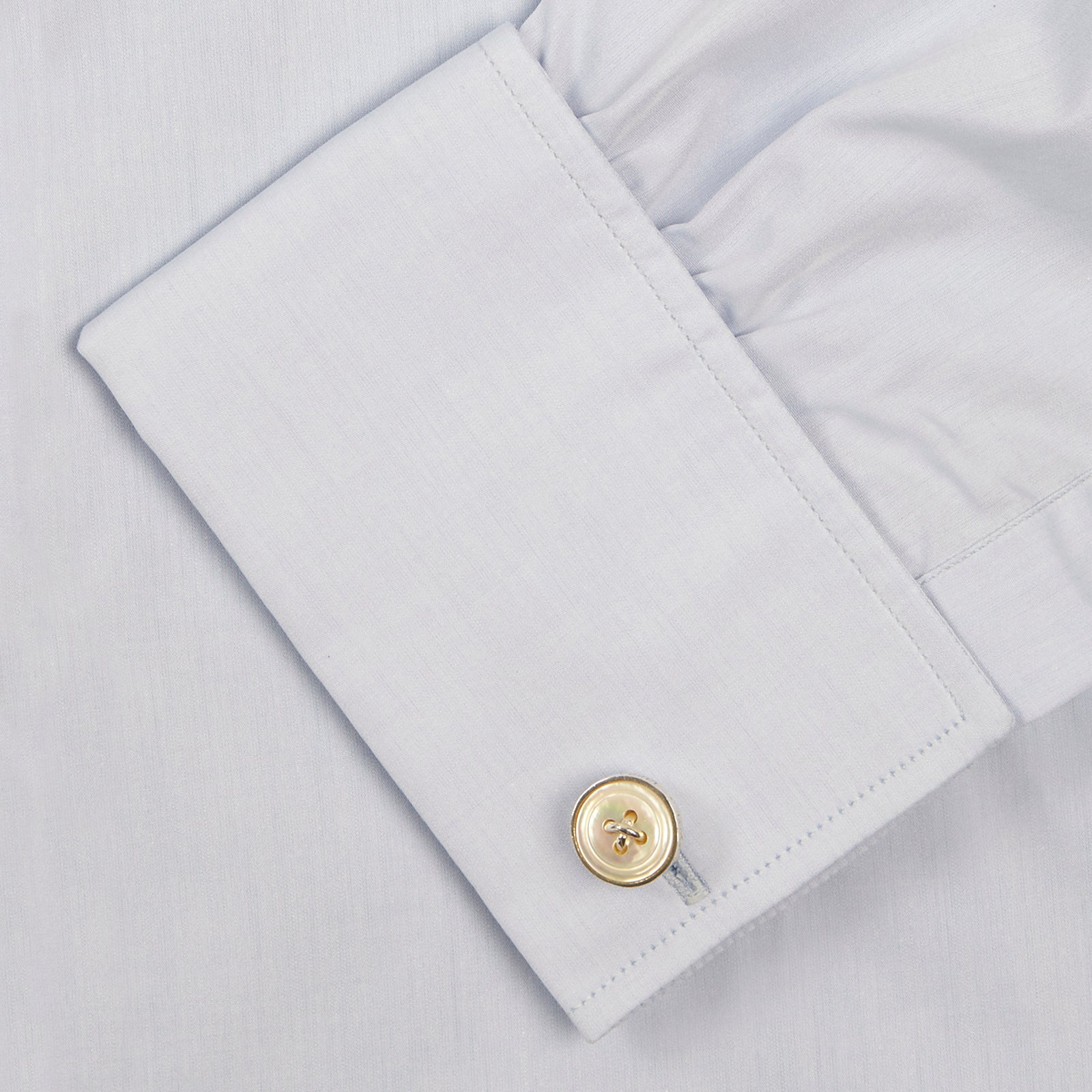 View 6 of product A neatly folded light blue long-sleeve dress shirt with a pointed collar and white buttons, styled with the Turnbull & Asser Monochrome Paisley Mill Silk Pocket Square (limited edition), displayed against a plain white background.