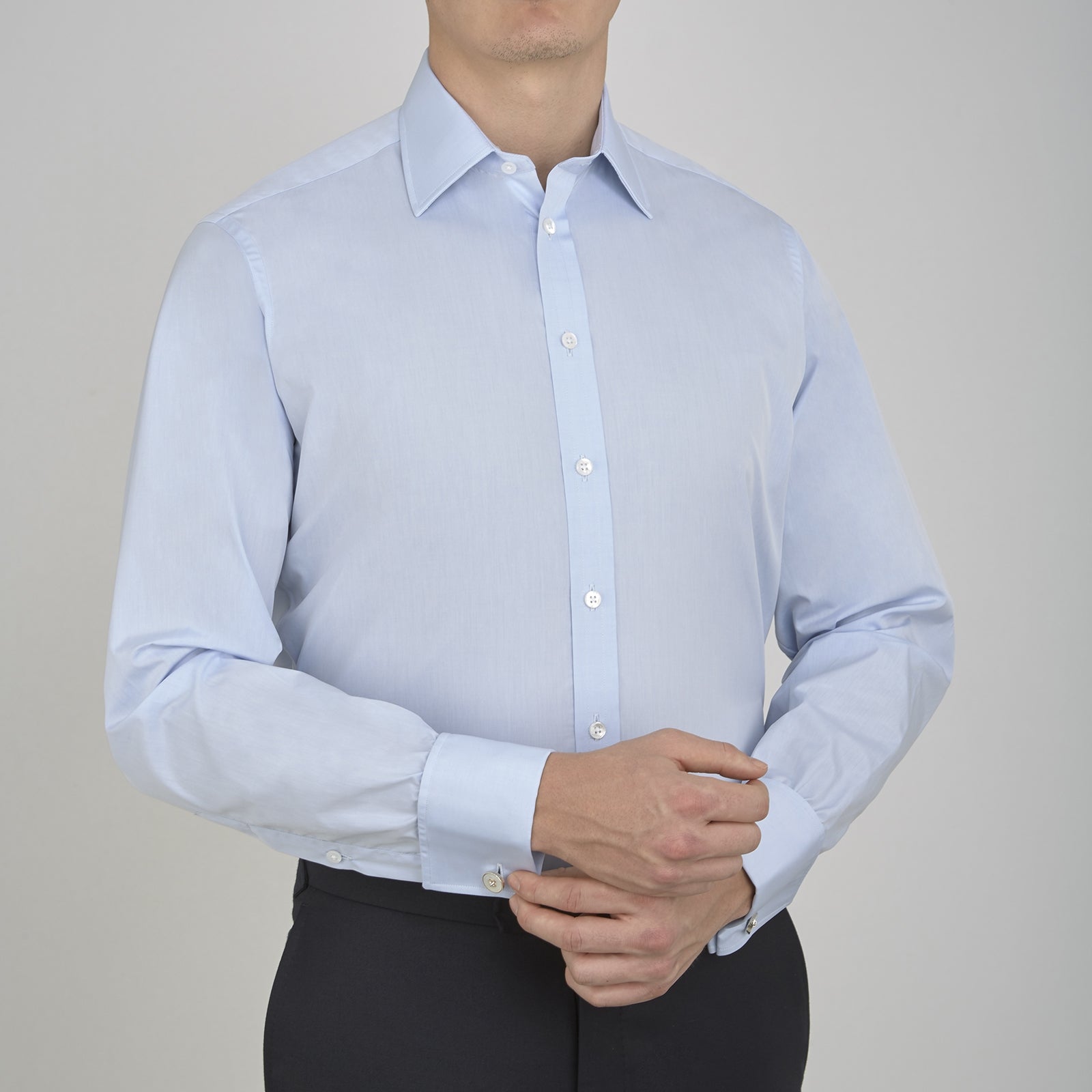 View 2 of product A neatly folded light blue long-sleeve dress shirt with a pointed collar and white buttons, styled with the Turnbull & Asser Monochrome Paisley Mill Silk Pocket Square (limited edition), displayed against a plain white background.