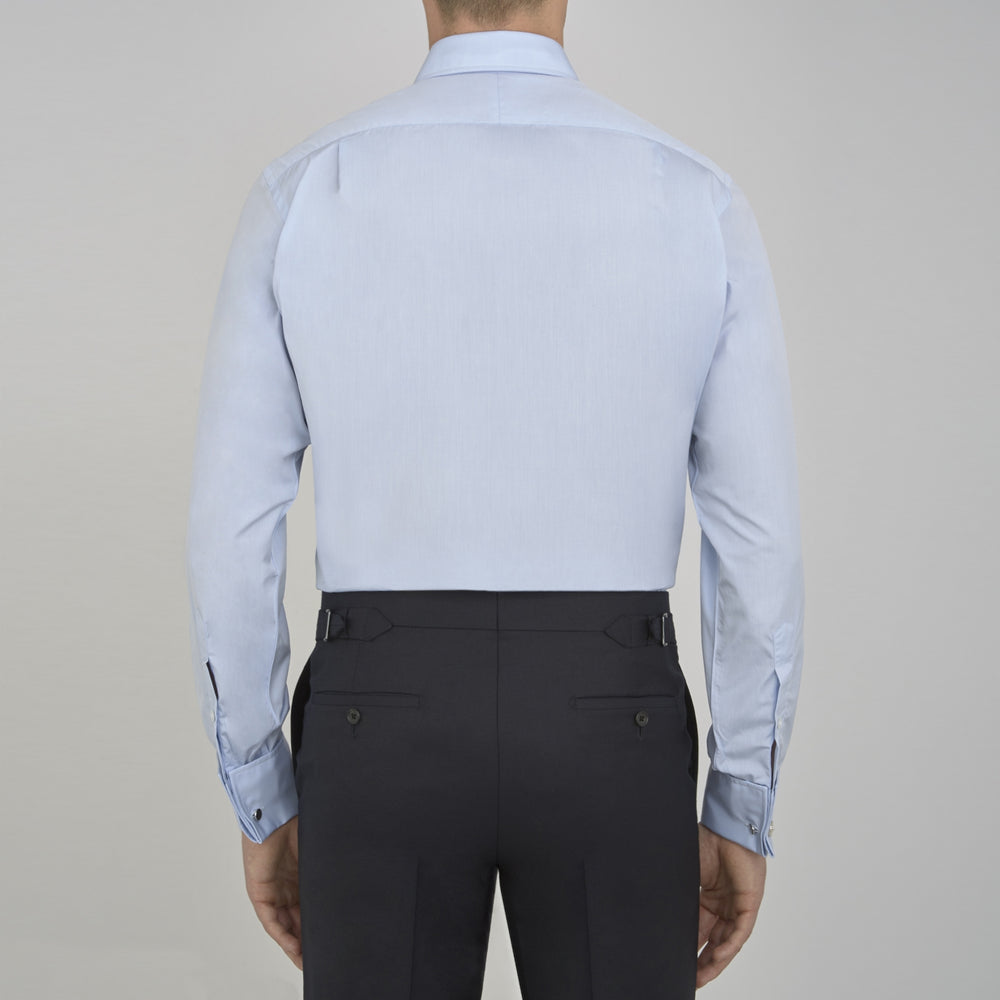 A neatly folded light blue long-sleeve dress shirt with a pointed collar and white buttons, styled with the Turnbull & Asser Monochrome Paisley Mill Silk Pocket Square (limited edition), displayed against a plain white background.