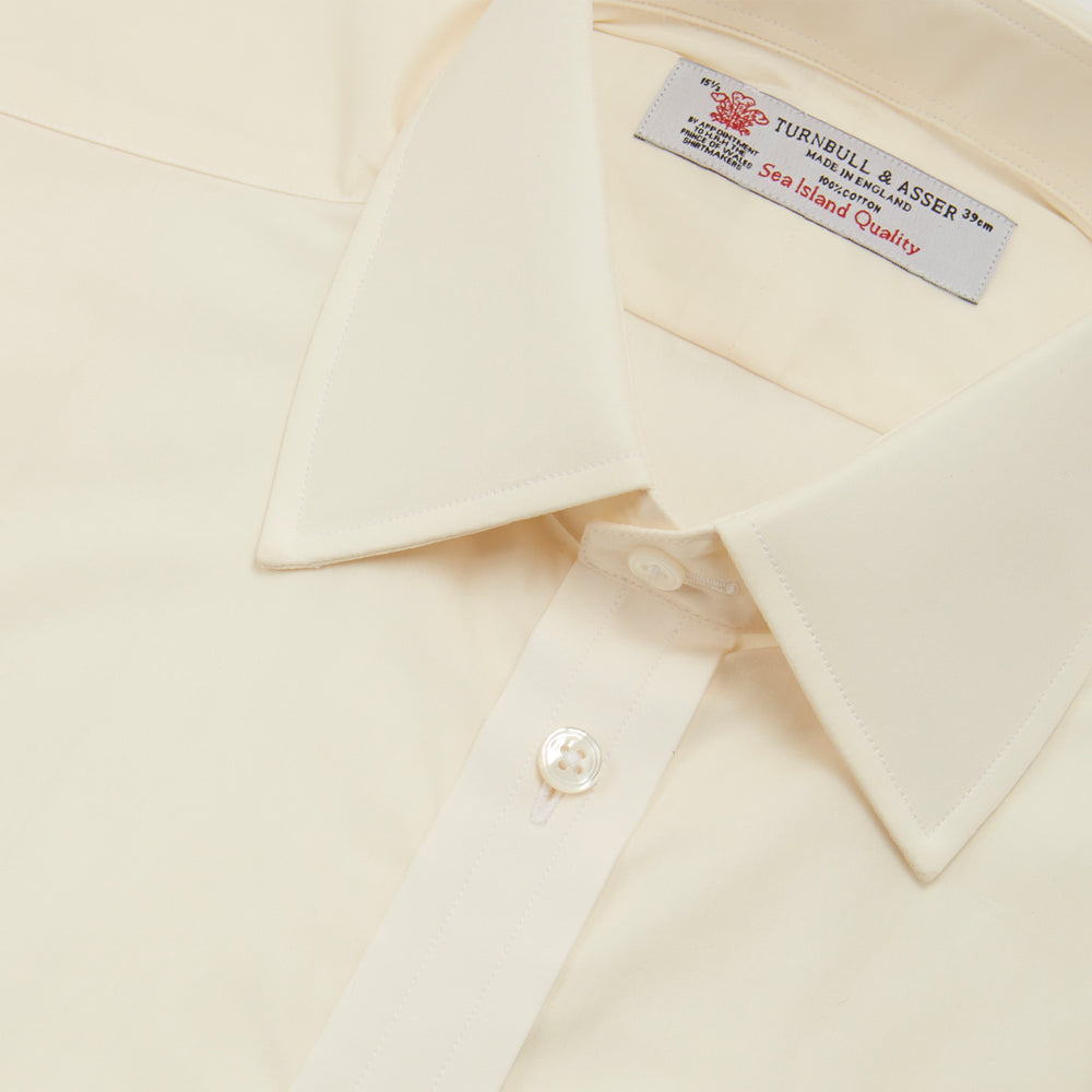 The Turnbull & Asser Cream Sea Island Quality Cotton Shirt features a T&A collar, double cuffs, and a button-down front, elegantly displayed against a white background.