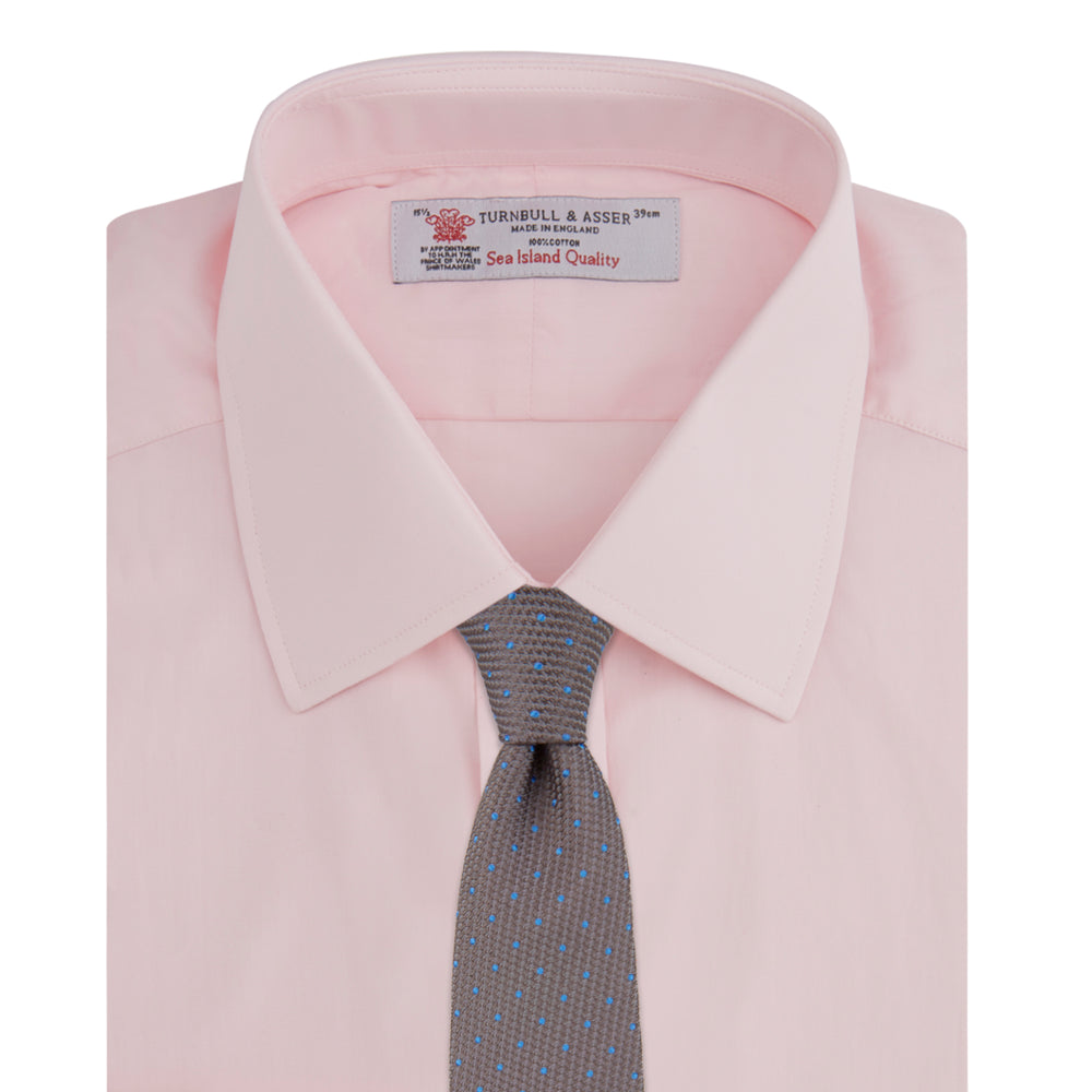 A slim black herringbone silk tie by Turnbull & Asser is paired with a neatly folded light pink long-sleeve dress shirt with a classic collar and white buttons, all displayed on a plain white background.