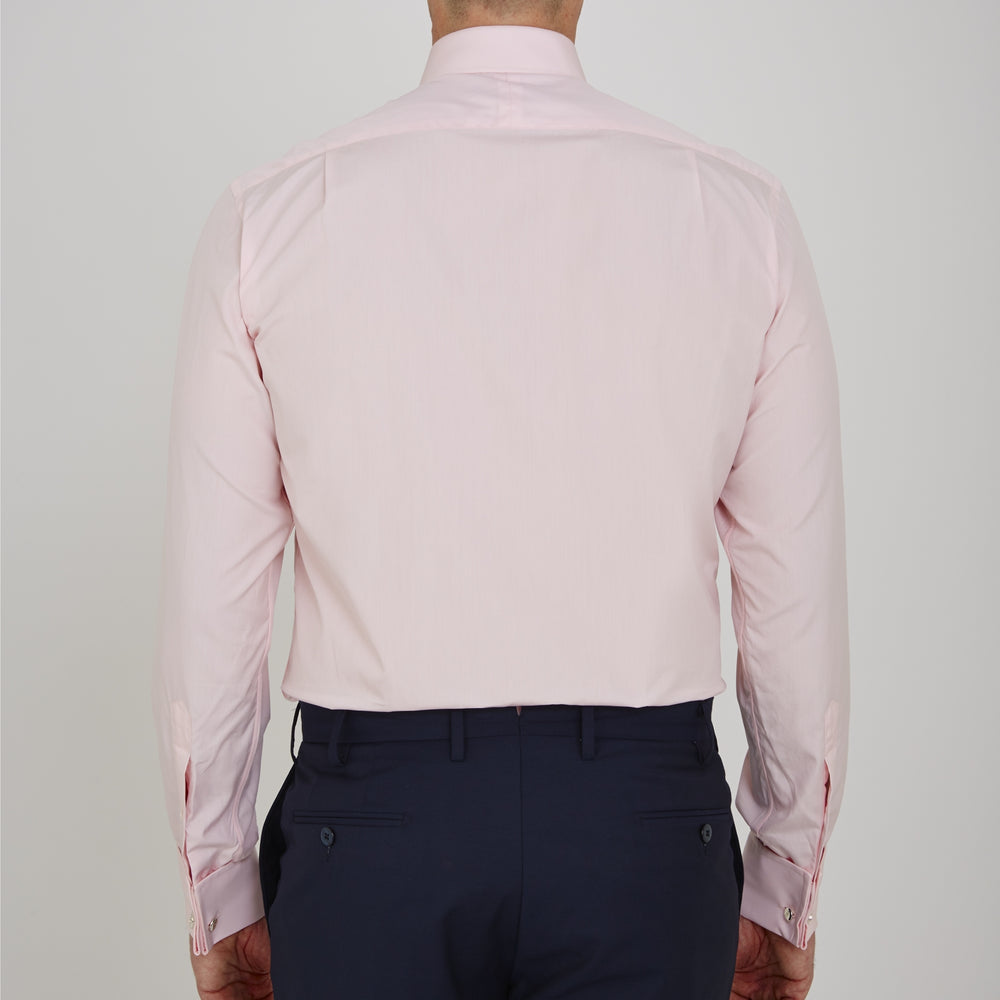 A slim black herringbone silk tie by Turnbull & Asser is paired with a neatly folded light pink long-sleeve dress shirt with a classic collar and white buttons, all displayed on a plain white background.