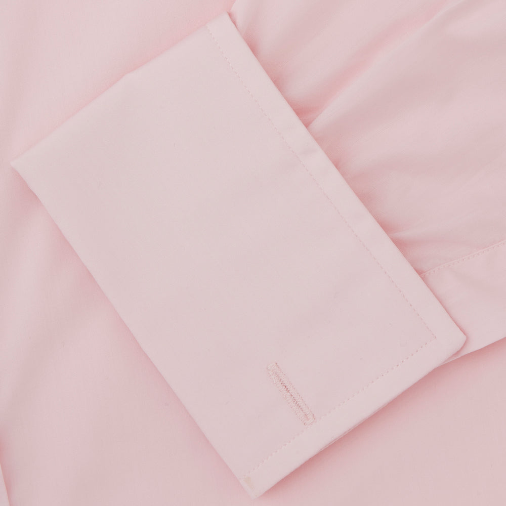 A slim black herringbone silk tie by Turnbull & Asser is paired with a neatly folded light pink long-sleeve dress shirt with a classic collar and white buttons, all displayed on a plain white background.