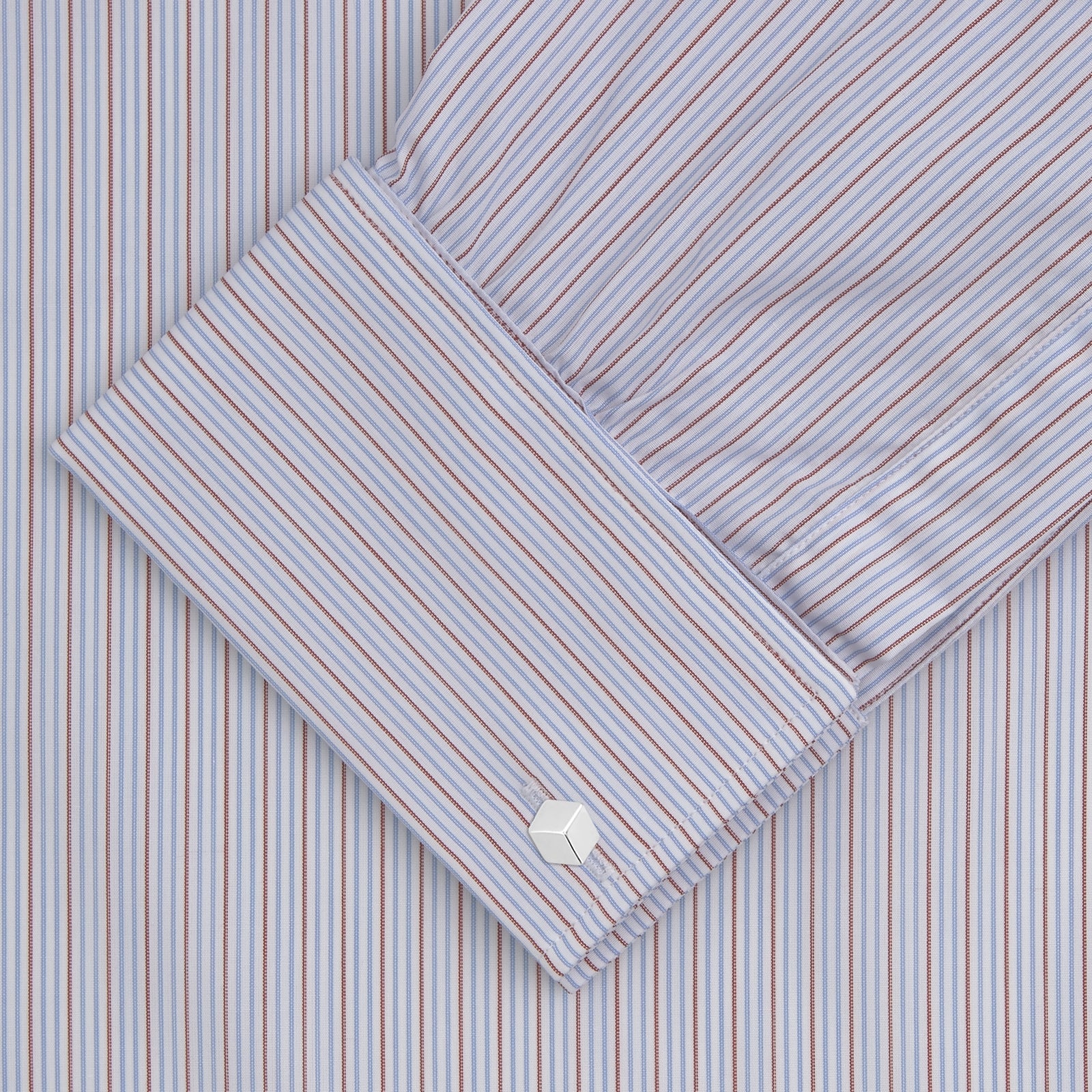 View 2 of product The Turnbull & Asser Red and Navy Supraluxe Stripe Shirt features a T&A collar, double cuffs, and thin vertical blue and red stripes on white premium cotton. Displayed folded against a plain white background.