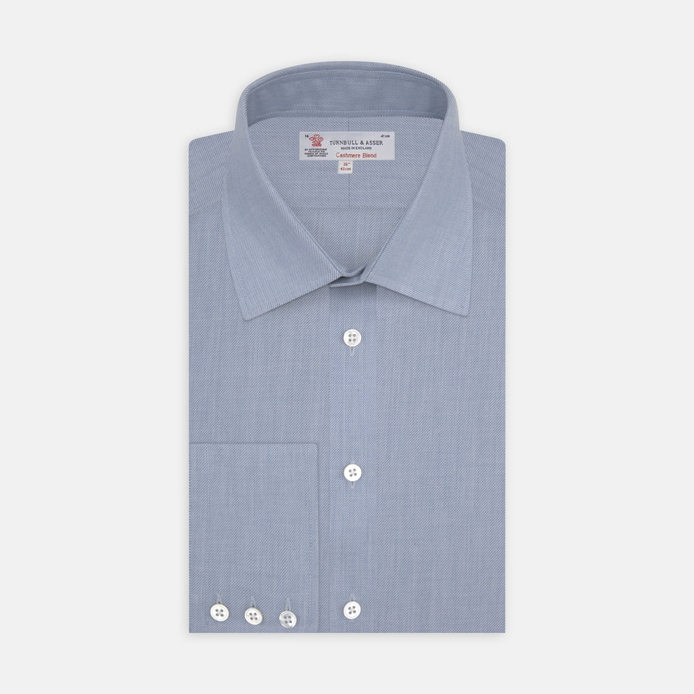 The Turnbull & Asser Blue Cashmere Blend Shirt features a T&A collar and 3-button cuffs, elegantly folded and showcased against a plain white background.